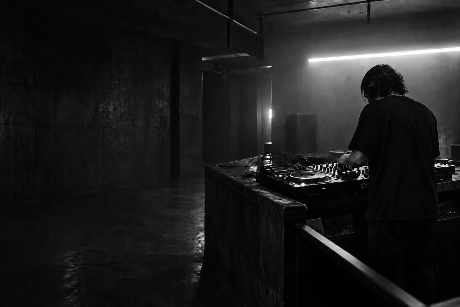 Sötét, ipari hangulatú klubtérben zenélő DJ